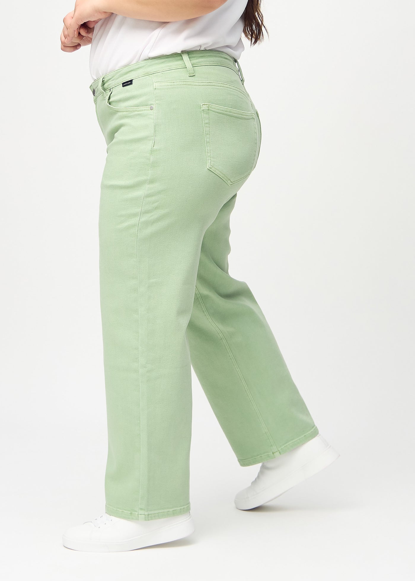 Lysegrønne loose jeans set fra siden på en plus-size model.