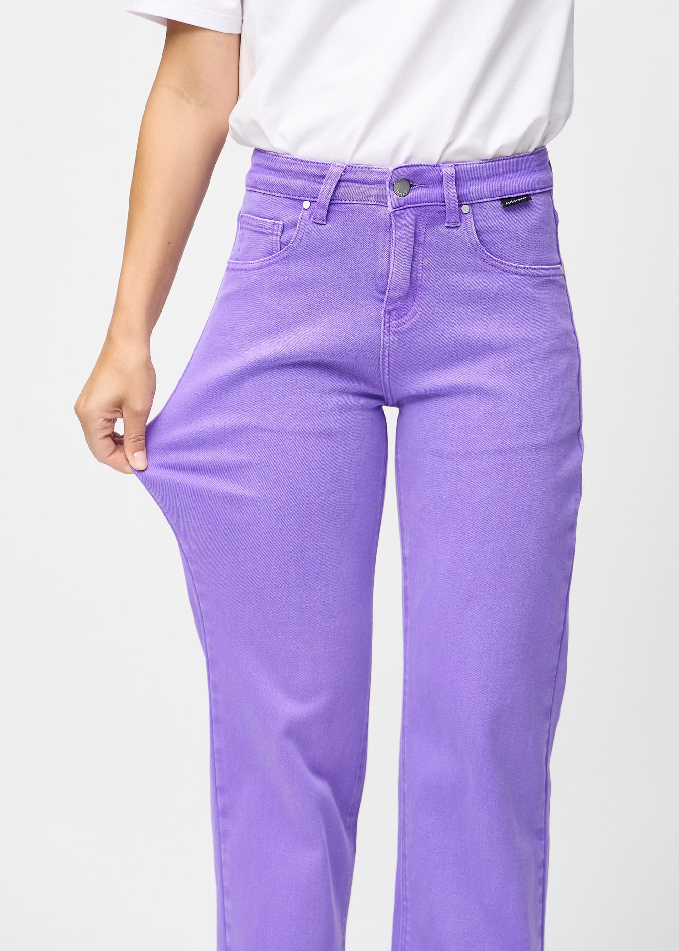 Model strækker jeansene ved låret for at vise stretch.