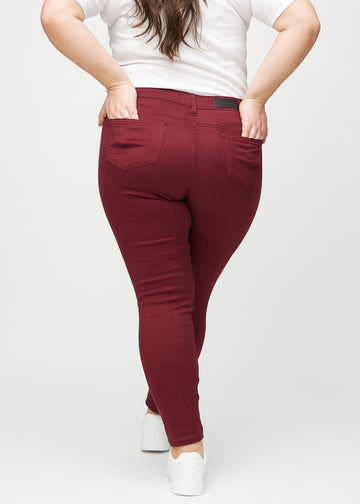 Mørkerøde skinny jeans set bagfra på en plus-size model, så man kan se hele produktet.