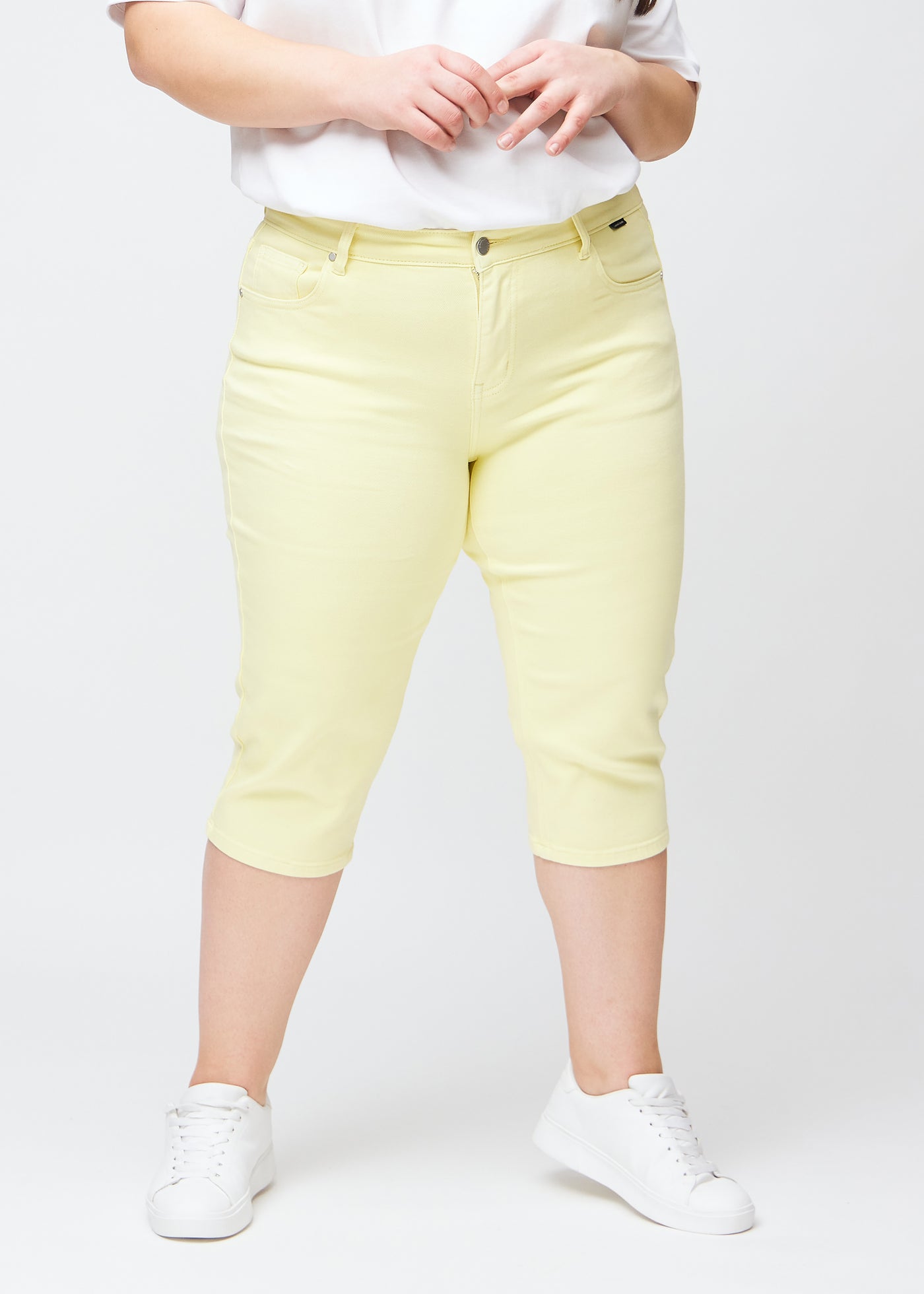 Lysegule slim capris, farve Lemonades, med tætsiddende pasform og længde lige under knæet – set forfra på plus-size model.