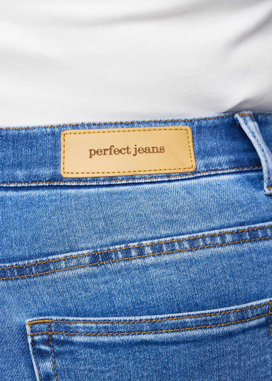 Close-up of blue denim with the Perfect Jeans leather patch at the back of the waistband on a plus-size model.