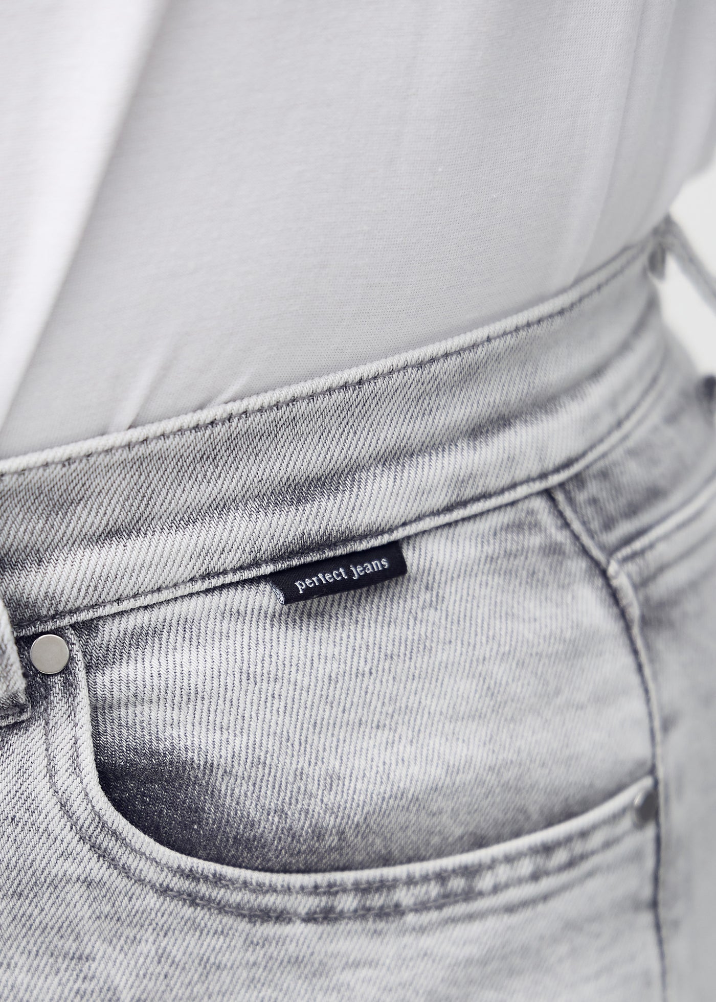 Forlommen på et par lysegrå denim middle shorts, hvor man kan se logoet.