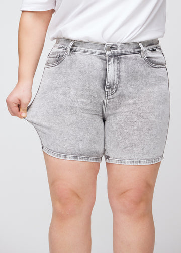 Plus-size model strækker shortsene ved låret for at vise stretch.