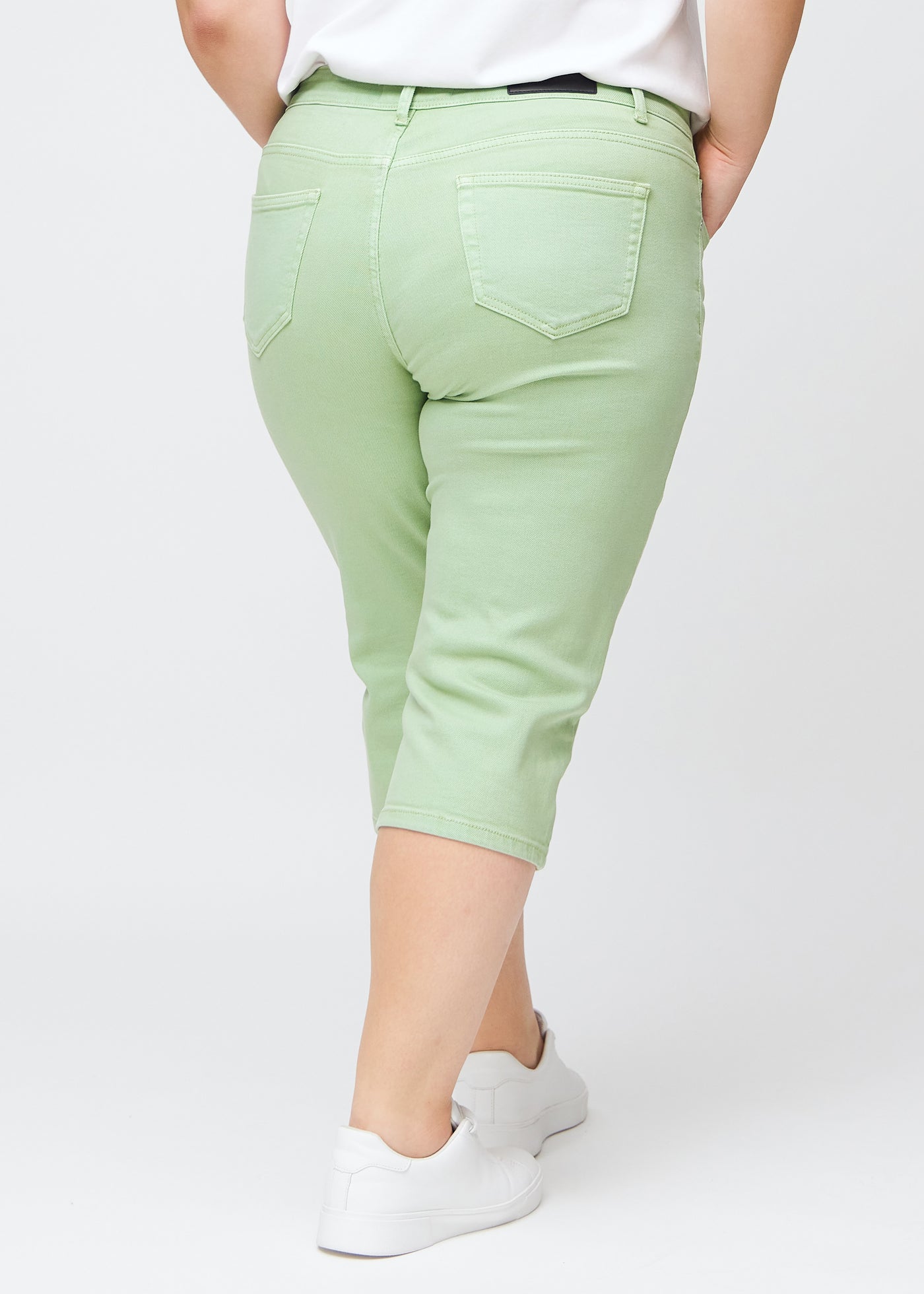 Lysegrønne slim capris set bagfra på en plus-size model – tydeligt billede af hele produktet og lommer.
