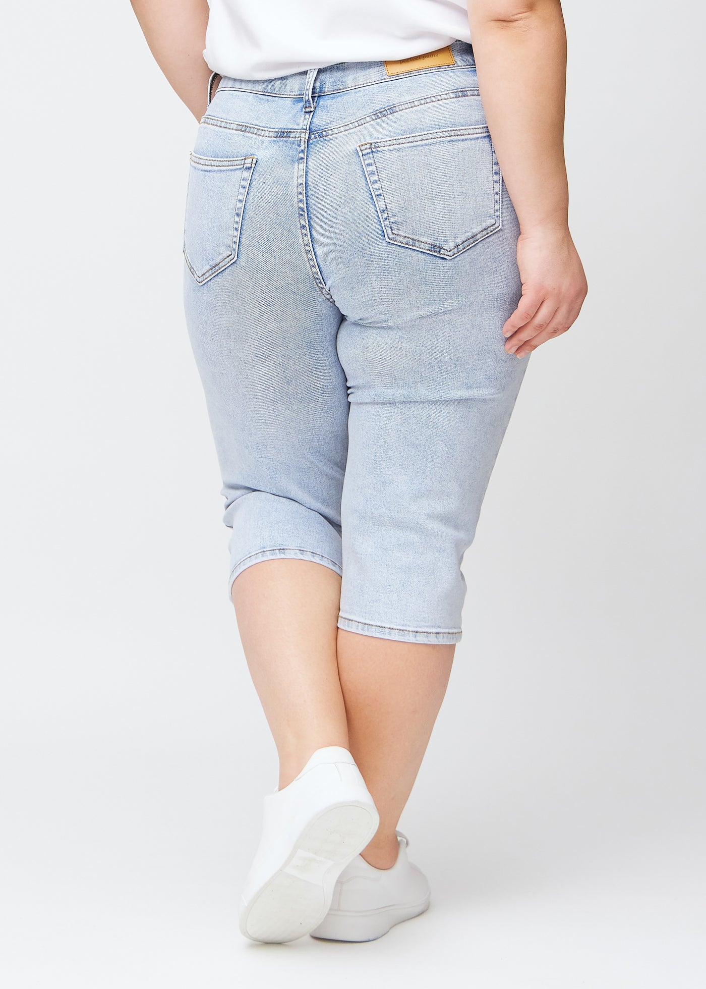 Lyseblå denim slim capris set bagfra på en plus-size model – tydeligt billede af hele produktet og lommer.