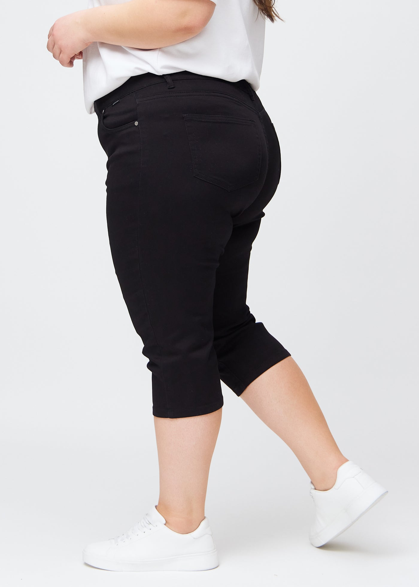 Sorte slim capris i farven Ravens – set fra siden på en plus-size model.