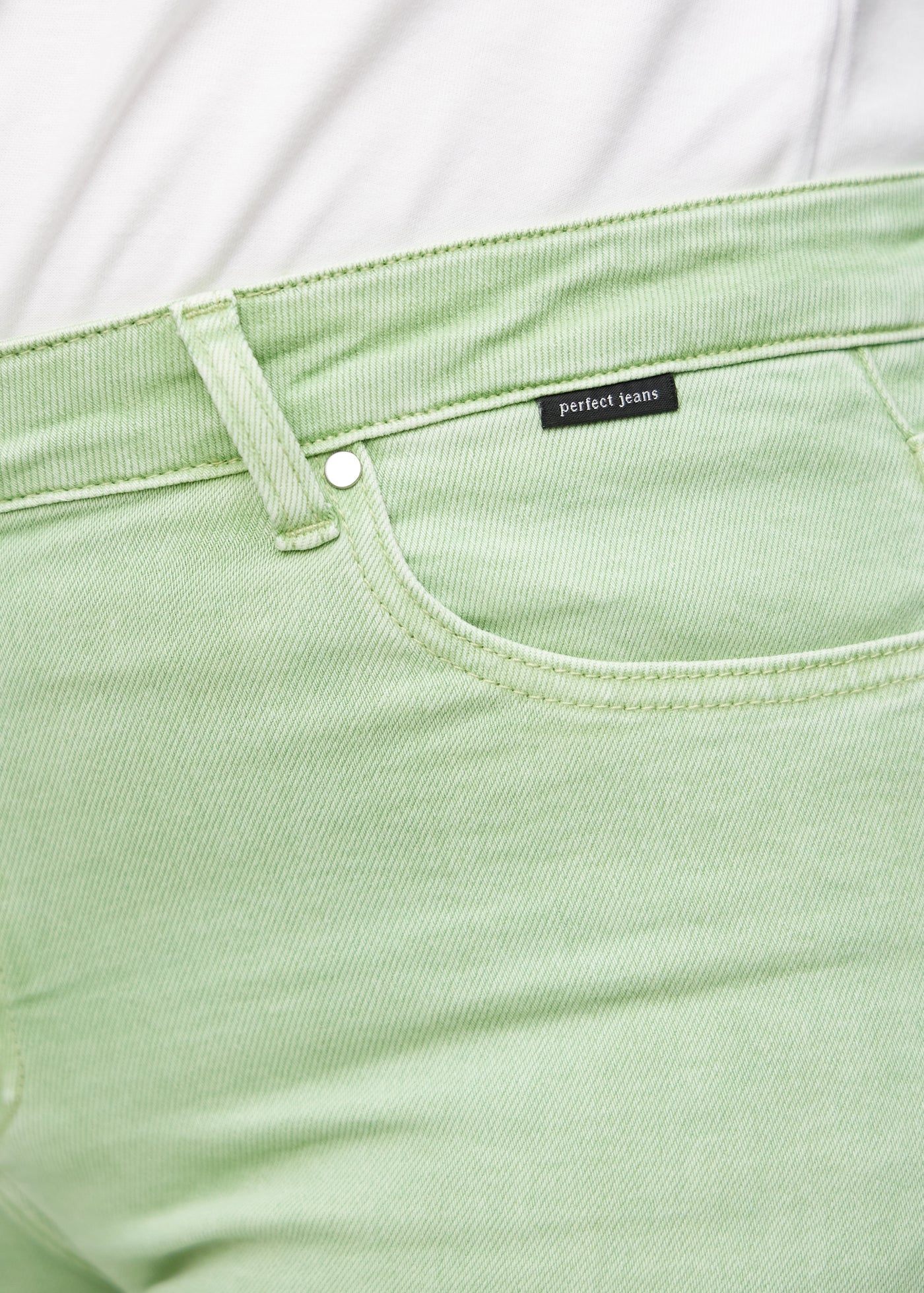 Forlommen på et par lysegrønne loose jeans, hvor man kan se logoet på en plus-size model.