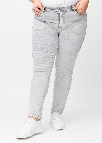 Lysegrå denim slim jeans, modelnavn Ashes, som sidder tæt til benet, dog lidt løsere ved anklen, på en plus-size model, set forfra.