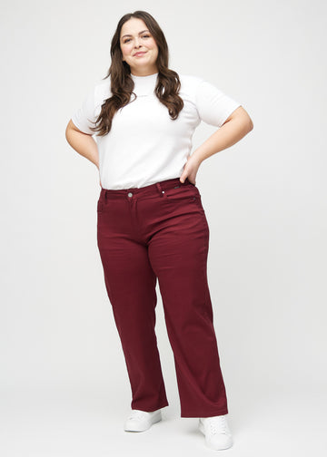 Fuldt billede af en plus-size model i mørkerøde loose jeans.