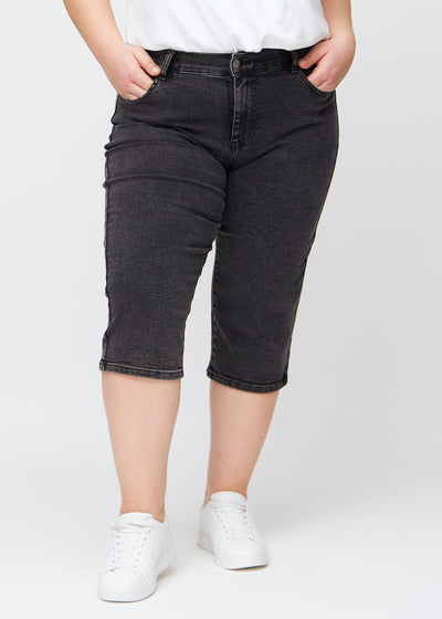 Mørkegrå denim slim capris, farve Shadows, med tætsiddende pasform og længde lige under knæet – set forfra på plus-size model.