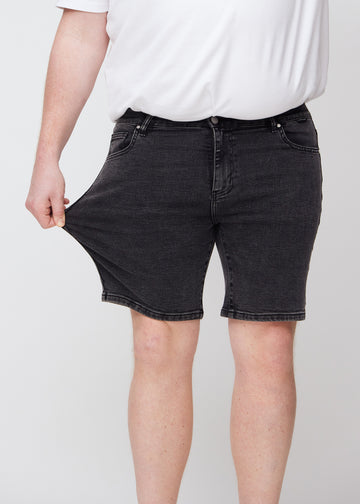 Plus-size model strækker shortsene ved låret for at vise stretch.