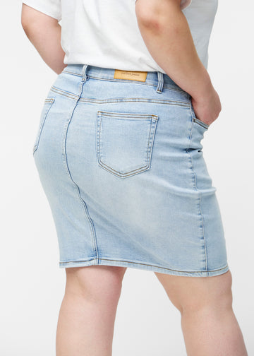 Lyseblå, tætsiddende og knælang denimnederdel set bagfra tæt på på plus-size model for at vise detaljer.