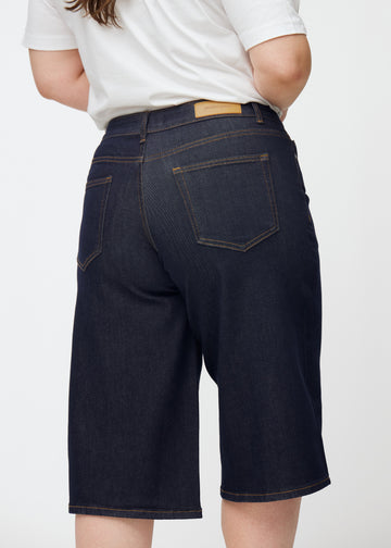 Deep dark blue denim capris for women in the colour Midnights seen from the back in close-up on a plus-size model.