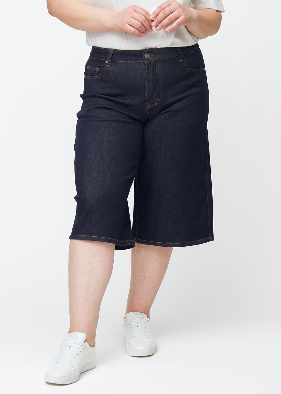 Deep dark blue denim capris for women in the colour Midnights with a loose fit seen from the front on a plus-size model.
