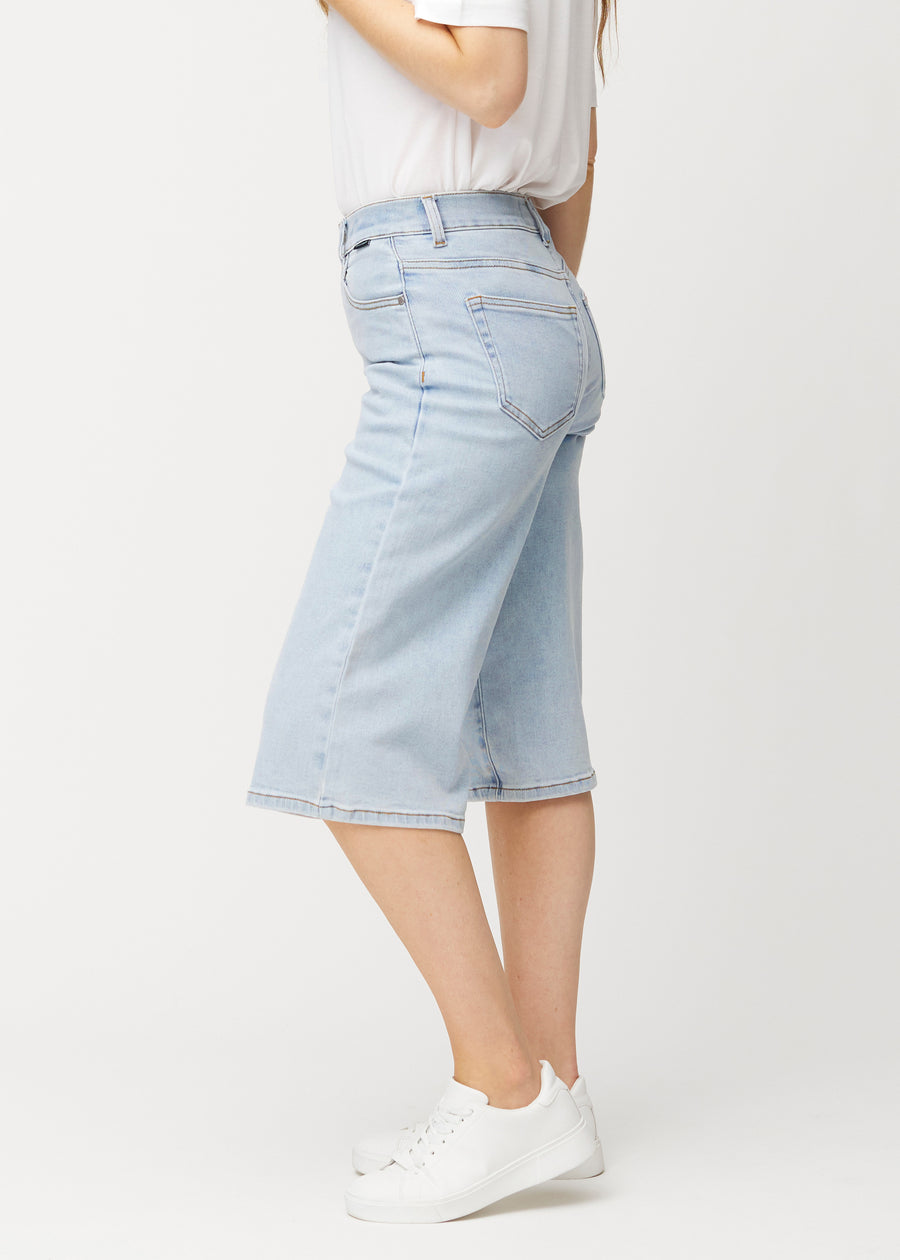 Side view of loose, light blue Waves denim capris on a model, showing the wide fit and length to just below the knee.
