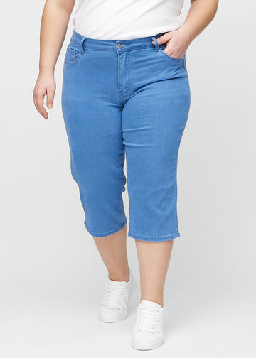 Blue regular capris, model name Geraniums, with a straight fit through the leg and ending just below the knee on a plus-size model, seen from the front.