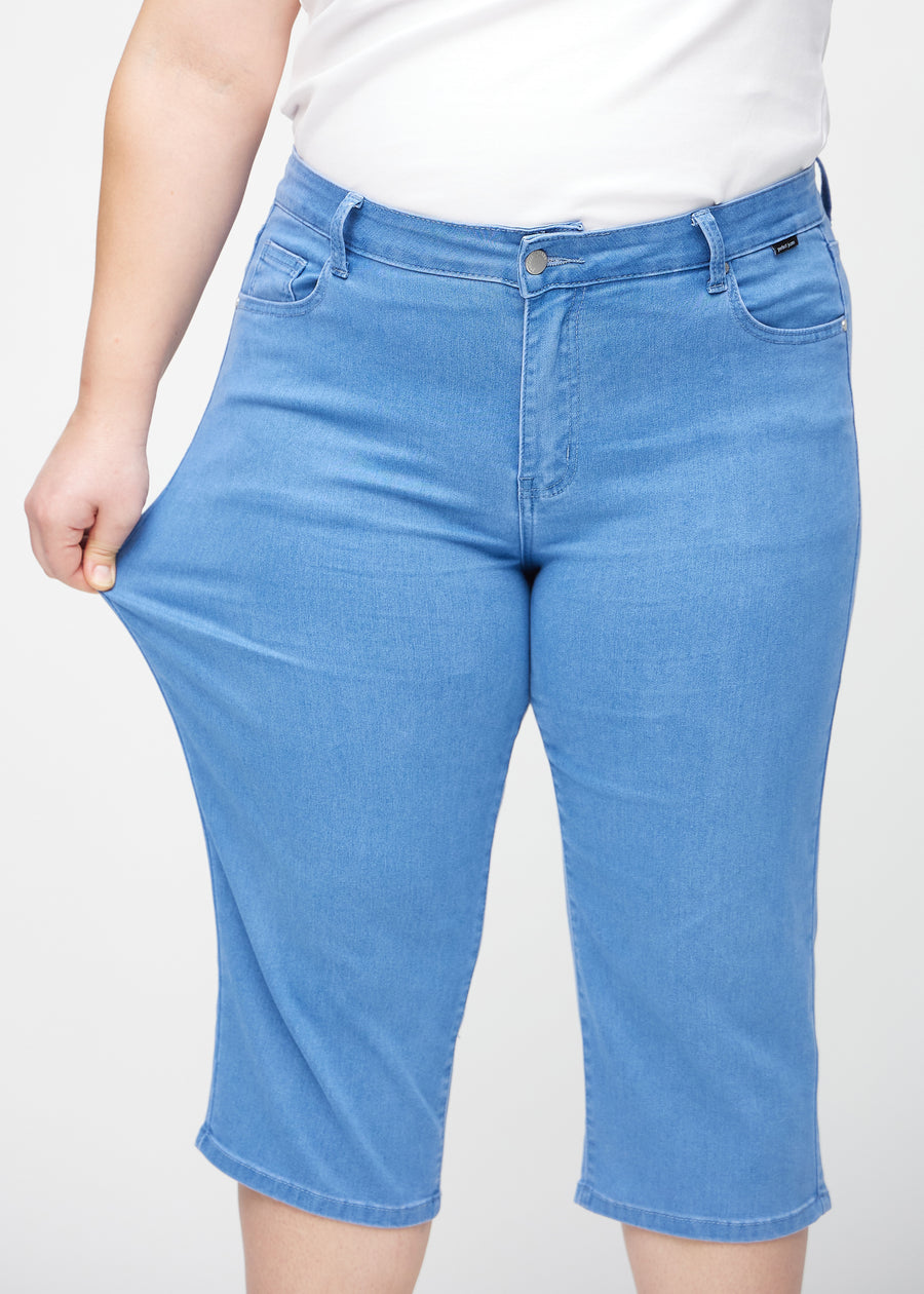 The plus-size model stretches the capris at the thigh to show the stretch.