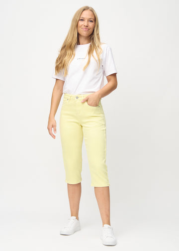 Full image of model wearing light yellow skinny capris.
