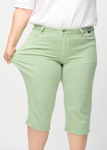 The plus-size model stretches the capris at the thigh to show the stretch.