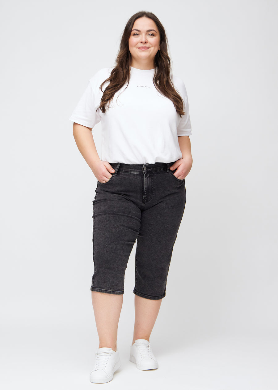 Full image of a plus-size model in dark grey denim regular capris.