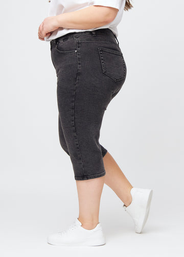 Dark grey denim regular capris seen from the side on a plus-size model.
