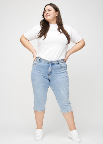 Full-length image of a plus-size model in light denim regular capris.