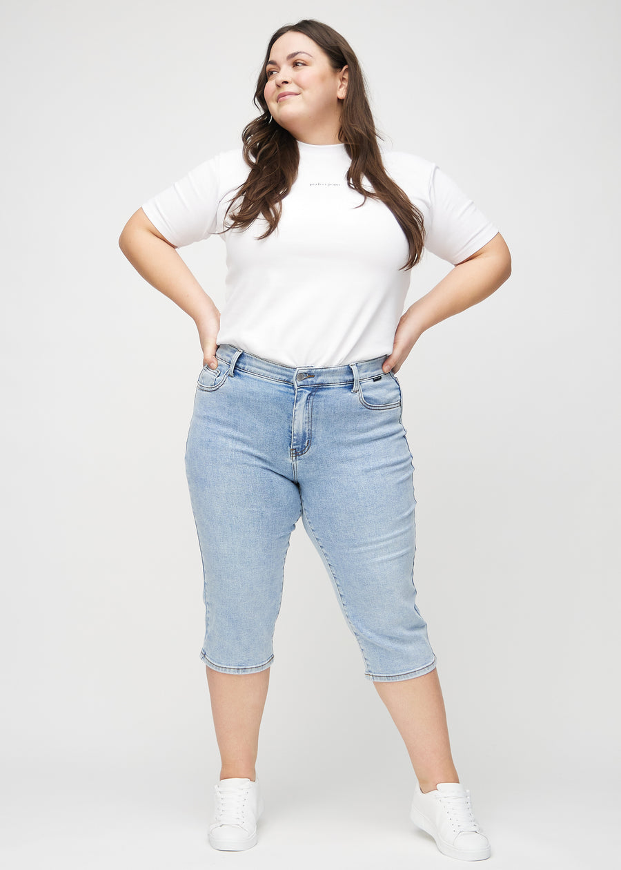 Full-length image of a plus-size model in light denim regular capris.