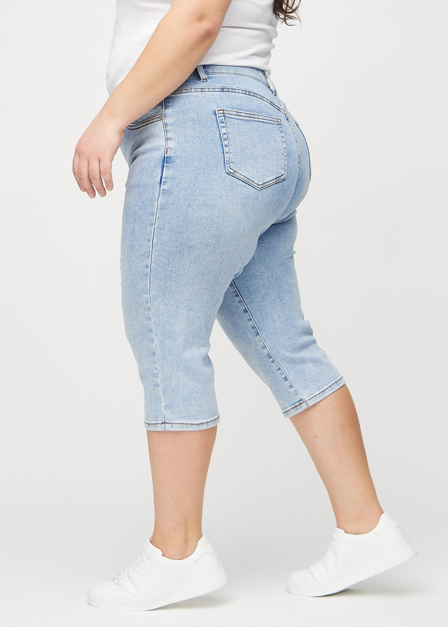 Light denim regular capris seen from the side on a plus-size model.