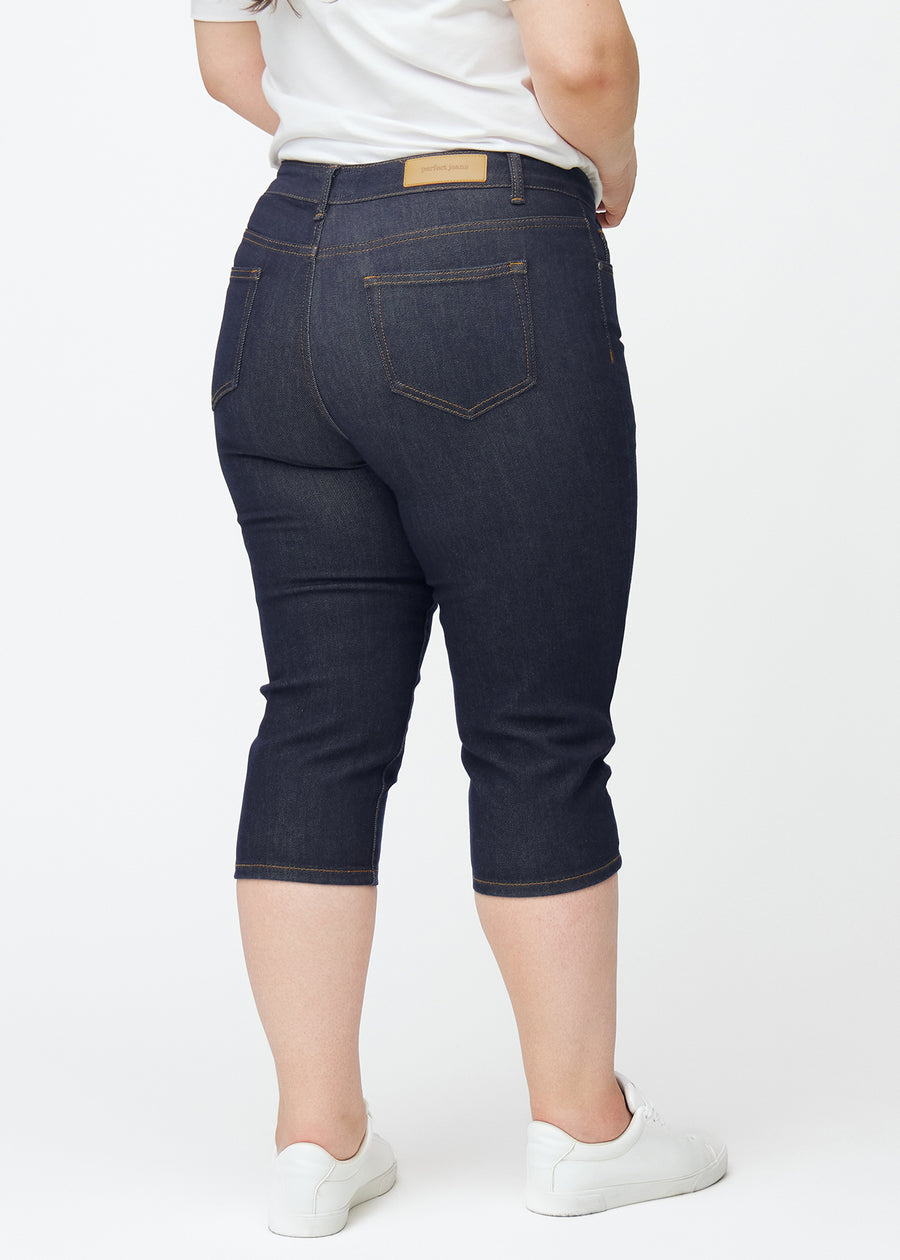 Deep dark blue denim capris for women in the colour Midnights seen from the back on a plus-size model.