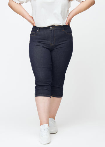 Deep dark blue denim capris for women in the colour Midnights with a skinny fit seen from the front on a plus-size model.