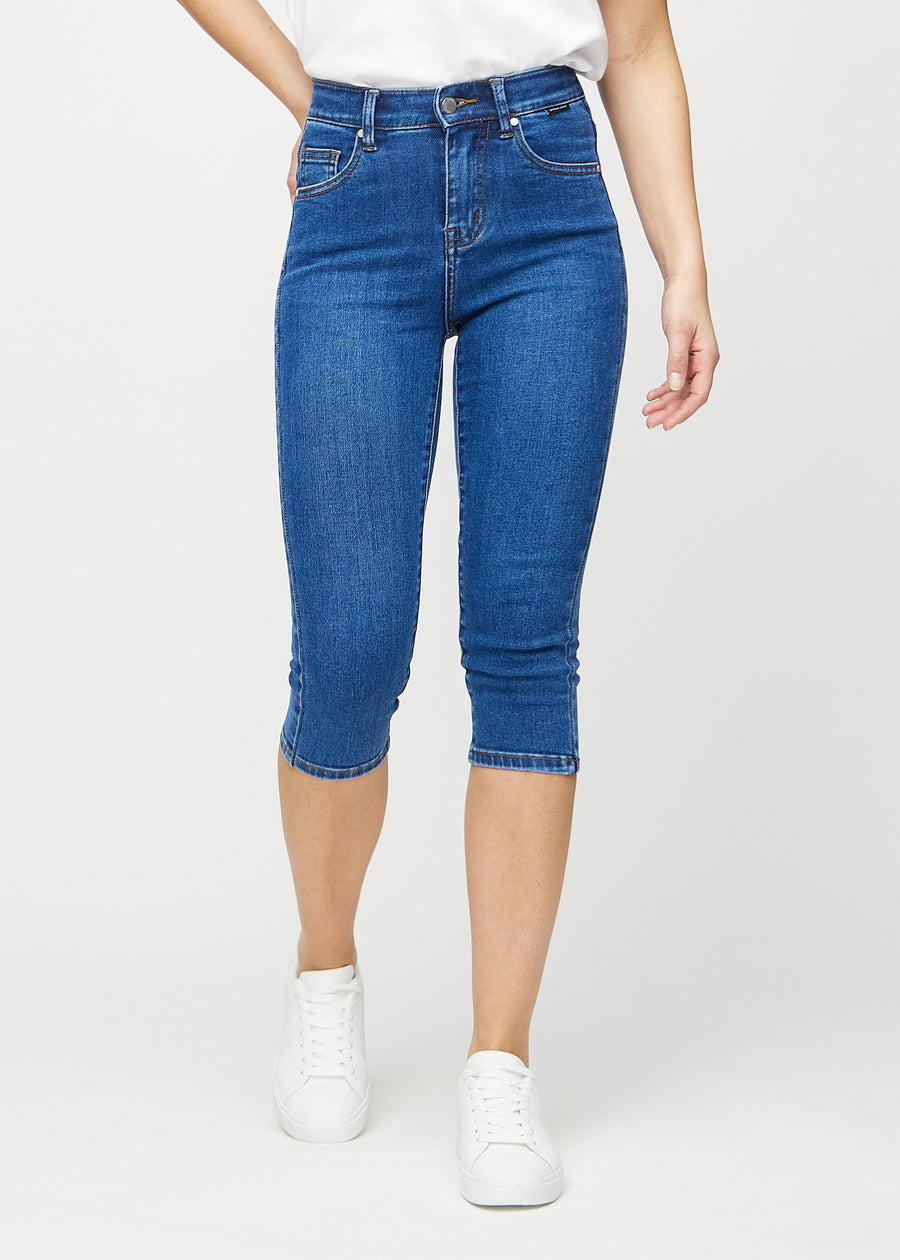 Skinny capris for women in dark blue denim, color Oceans. Front view on a model, showing the close-fitting legs ending just below the knee.