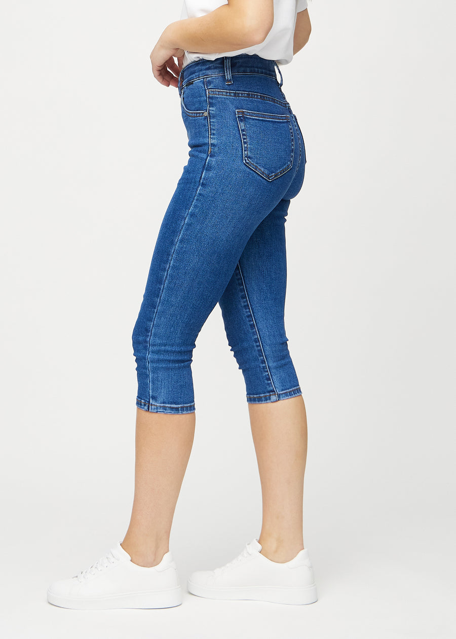 Skinny capris for women in dark blue denim, color Oceans. Side view on a model, showing the fitted cut.