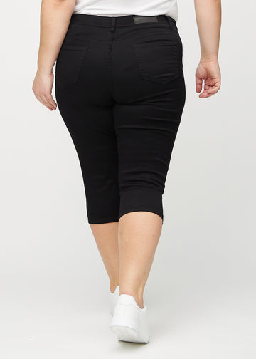 Skinny capris for women in black fabric, color Ravens. Back view on a plus-size model, showing the fit and back pockets.