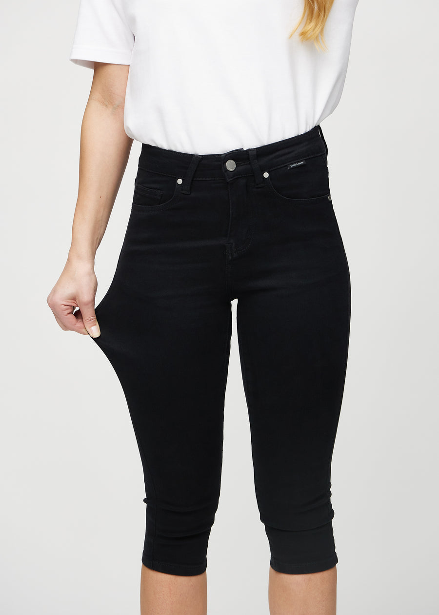 Skinny capris for women in black fabric, color Ravens. A model stretches the fabric to demonstrate its flexibility.