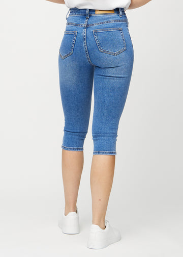 Skinny capris for women in blue denim, color Rivers. Back view on a model, showing the fit and back pockets.