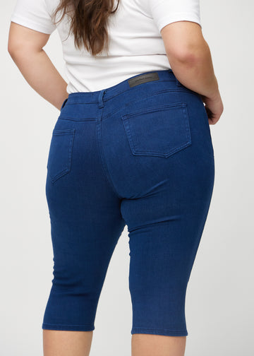 Dark blue skinny capris seen from the back close up on a plus-size model to show details.
