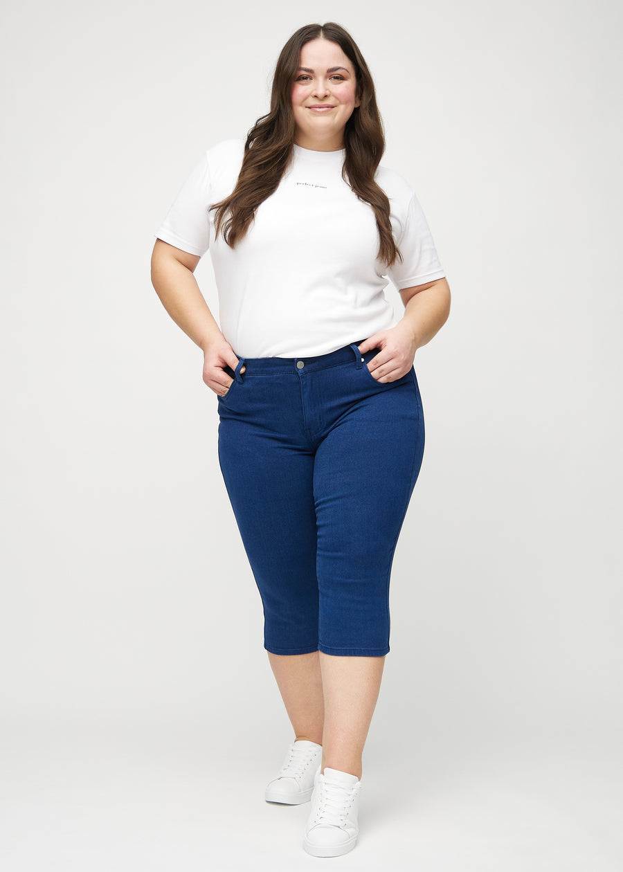 Full image of a plus-size model in dark blue skinny capris.