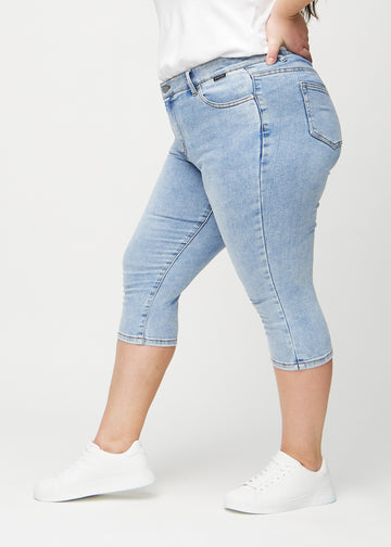 Skinny capris for women in light blue denim, color Waves. Side view on a plus-size model, showing the fitted cut.