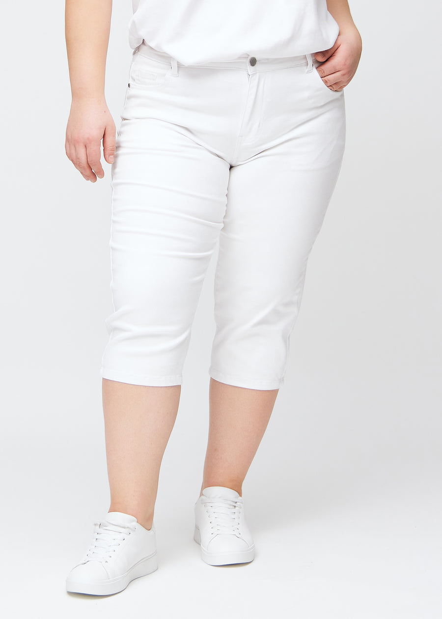 Slim capris for women in white jeans fabric, color Marguerites. Front view on a plus-size model, showing the fitted cut ending just below the knee.
