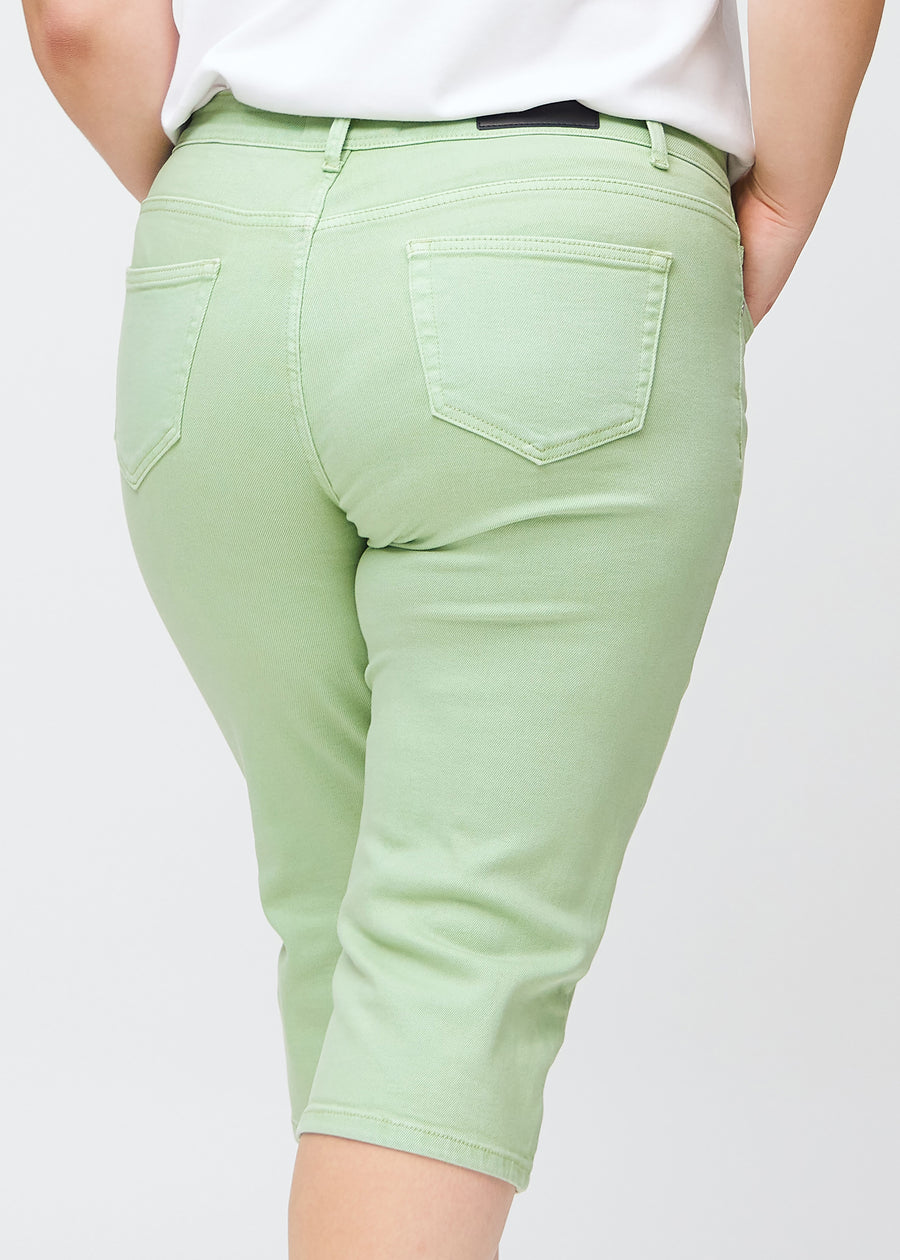 Slim capris for women in pastel light green jeans fabric, color Mints. Close-up from behind on a plus-size model, highlighting the back pockets and stitching.