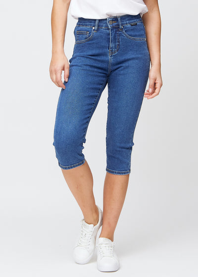Slim capris for women in dark blue denim, color Oceans. Front view on a model, showing the fitted cut ending just below the knee.