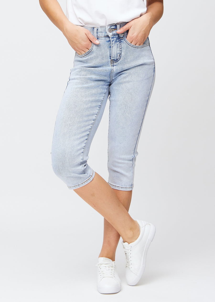Slim capris for women in light blue denim, color Waves. Front view on a model, showing the fitted cut ending just below the knee.
