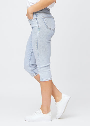 Slim capris for women in light blue denim, color Waves. Side view on a model, showing the tailored fit and mid-rise waist.
