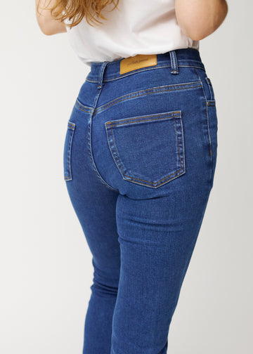Dark blue mid-rise bootcut jeans in Oceans. Close-up back view on a model, showing the details.
