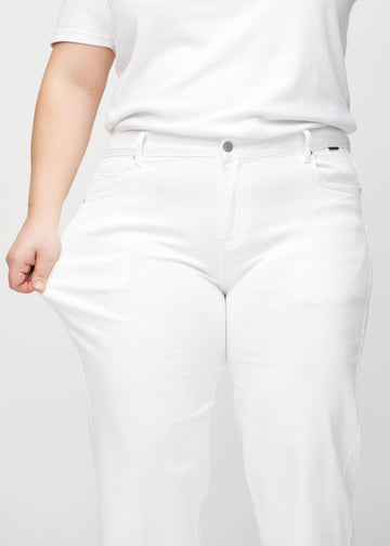 Loose jeans for women in white, color Marguerites. A plus-size model stretches the denim at the thigh to show the fabric&