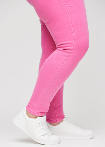 Skinny jeans for women in light pink, color Flamingos. Close-up of the snug-fitting leg openings at the ankles on a plus-size model.