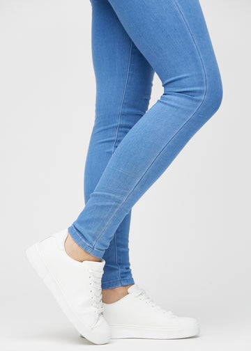 Skinny jeans for women in blue, color Geraniums. Close-up at the ankles on a model, showing the close-fitting leg openings.