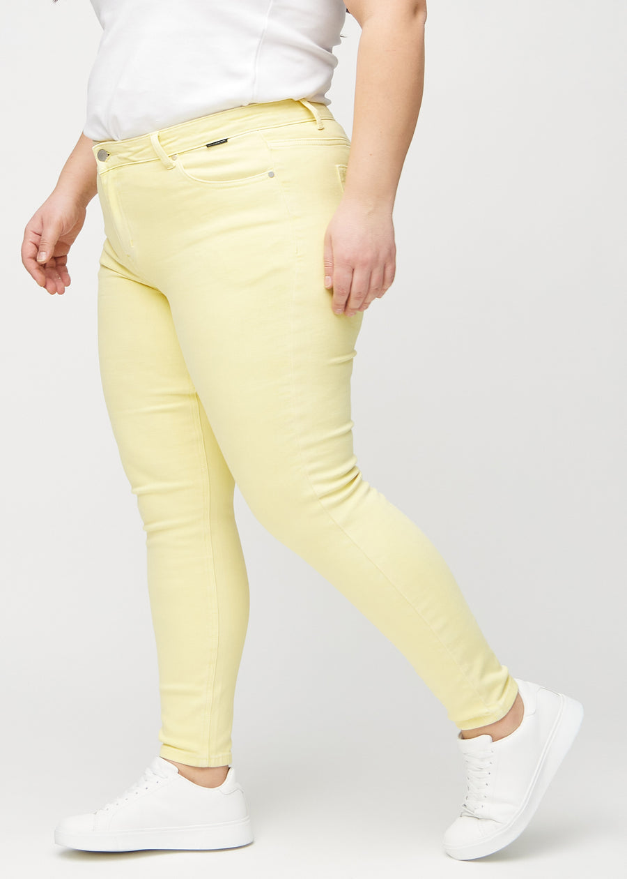 Skinny jeans for women in light yellow, color Lemonades. Side view on a plus-size model.
