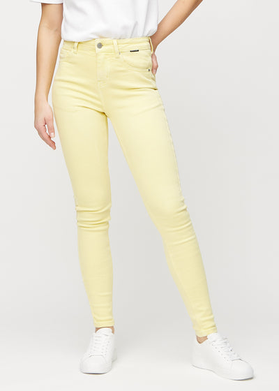 Skinny jeans for women in light yellow, color Lemonades. Front view on a model, showing the close fit through the legs.