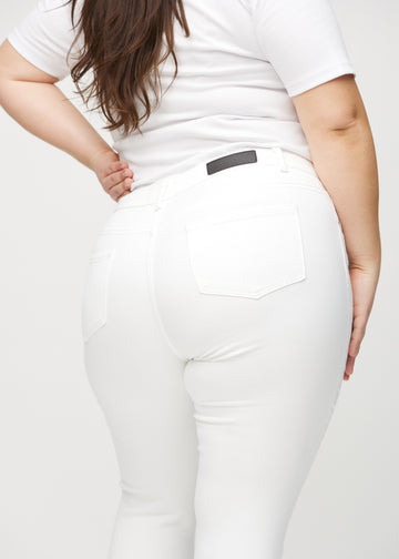 Skinny jeans for women in white, color Marguerites. Close-up back view on a plus-size model, showing details.